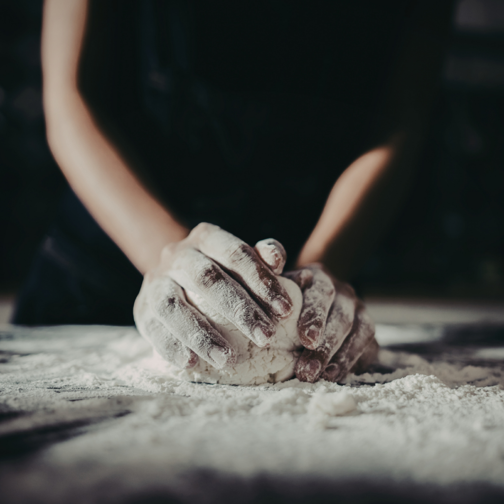 mani femminili che cucinano e impastano la pasta